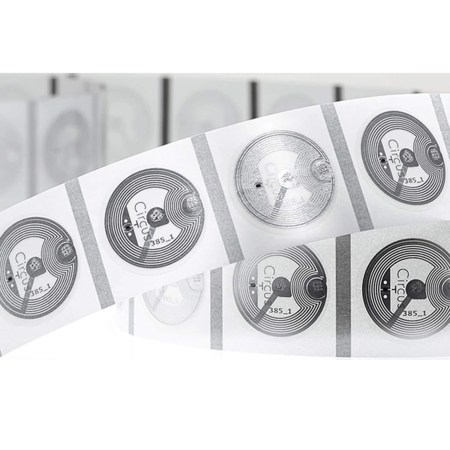 A roll of transparent circular NFC stickers with visible circuitry and printed text.