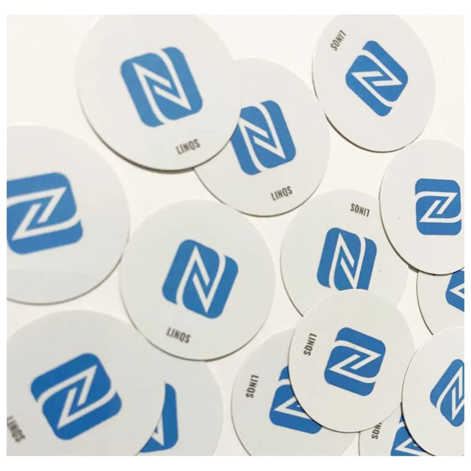 Round white stickers with a blue "N" logo and "LINQS" text scattered on a white surface.