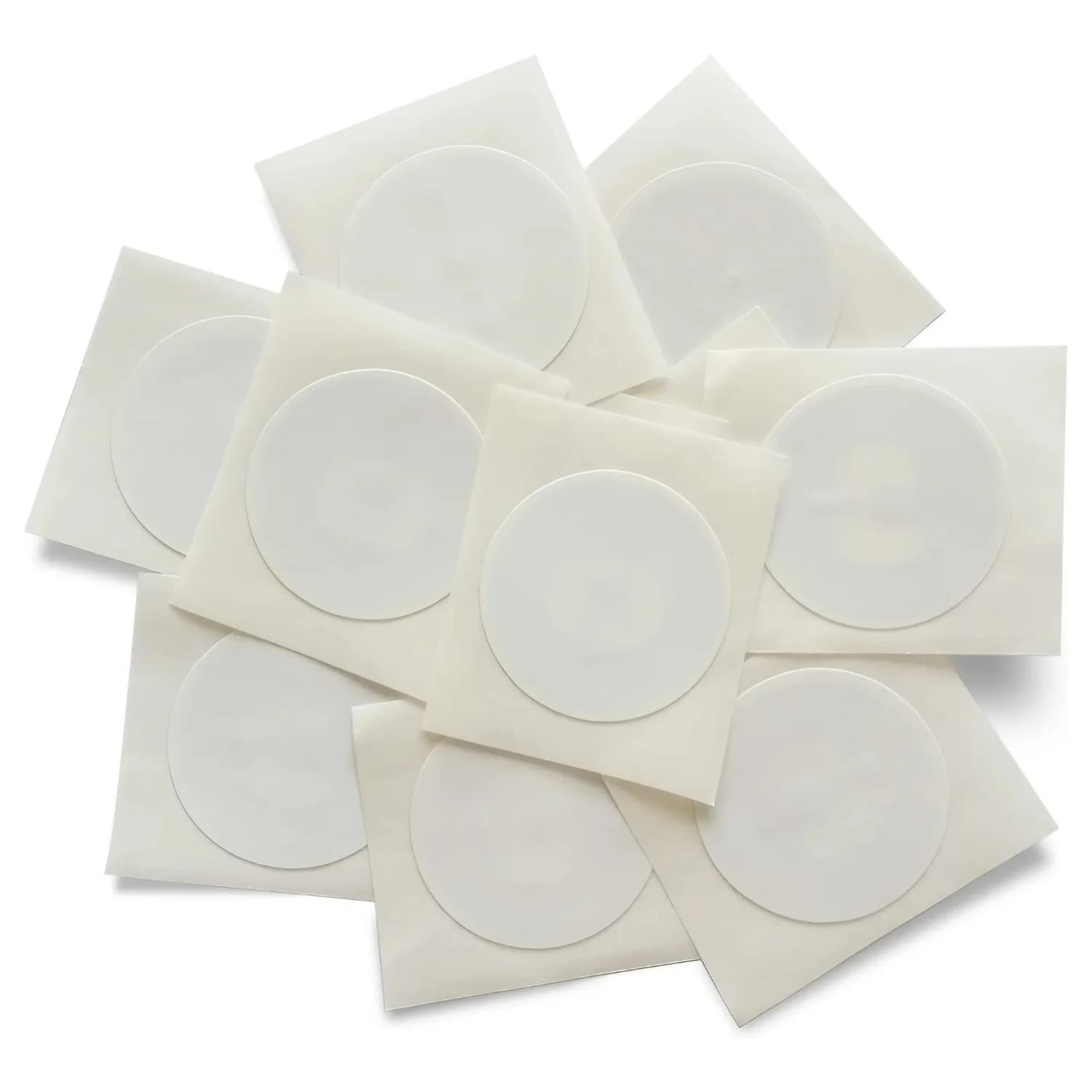 A stack of white, circular paper stickers on individual square sheets, arranged in a scattered pile.