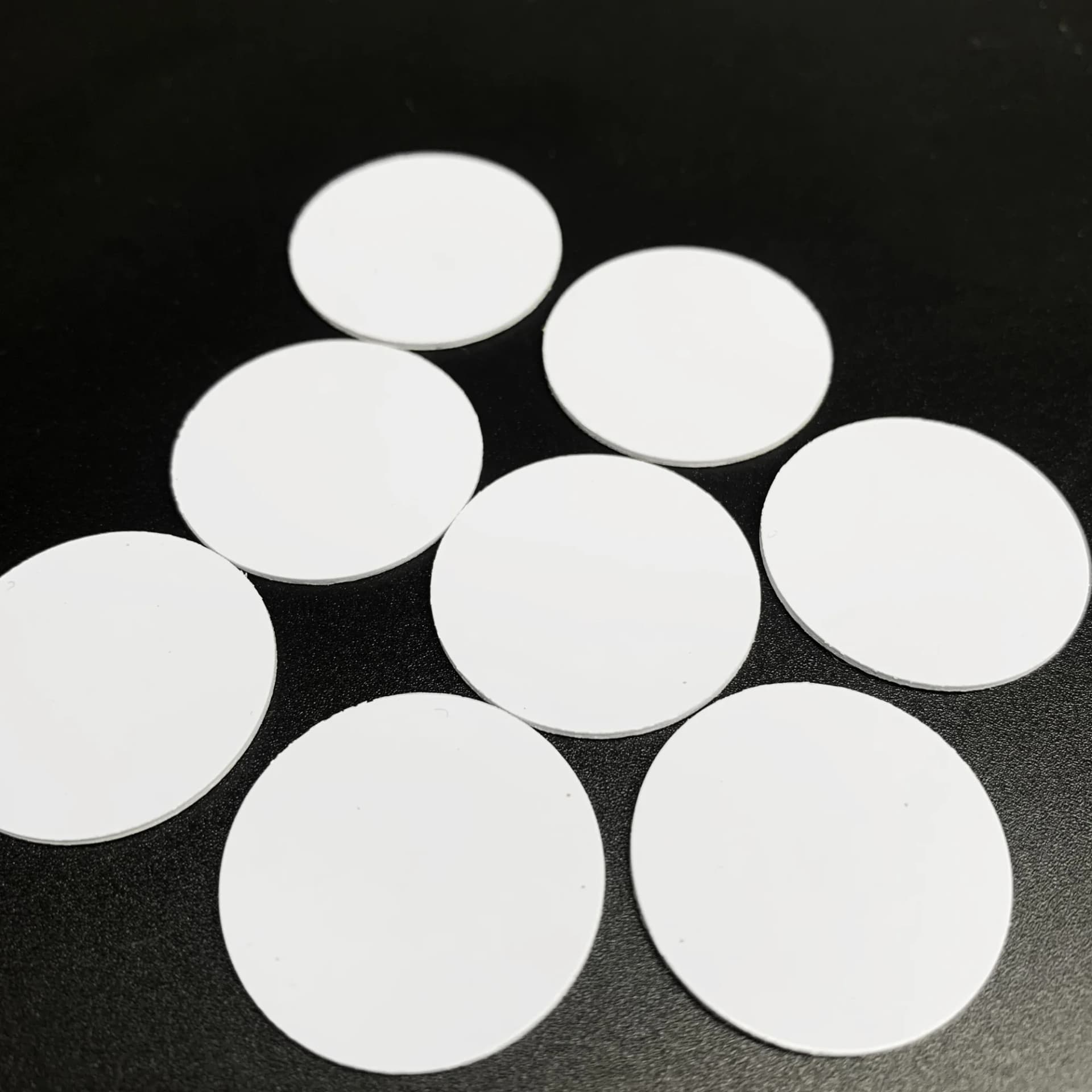 White circular NFC coin tags arranged on a black surface.